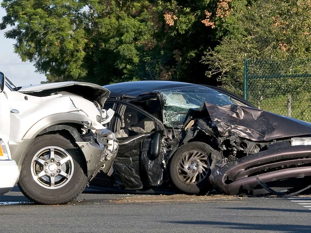 a car accident between a white truck and a black sedan
