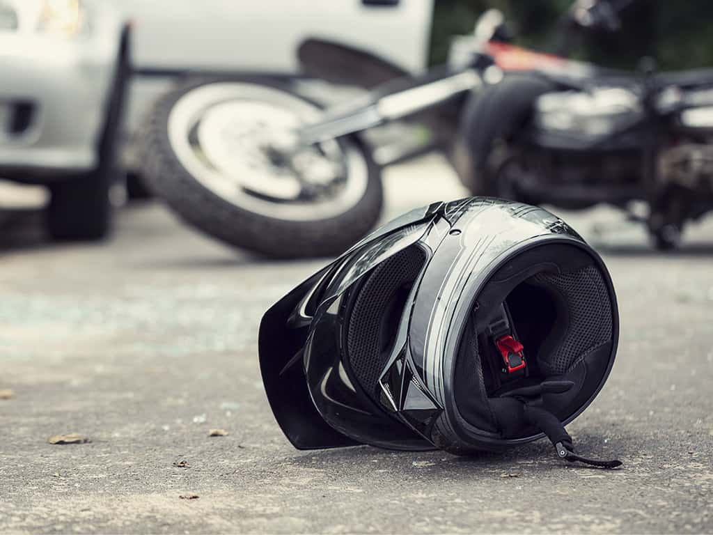 motorcycle accident: A motorcycle knocked over on the side of the road, with the bike tipped over, and an empty helmet on the pavement